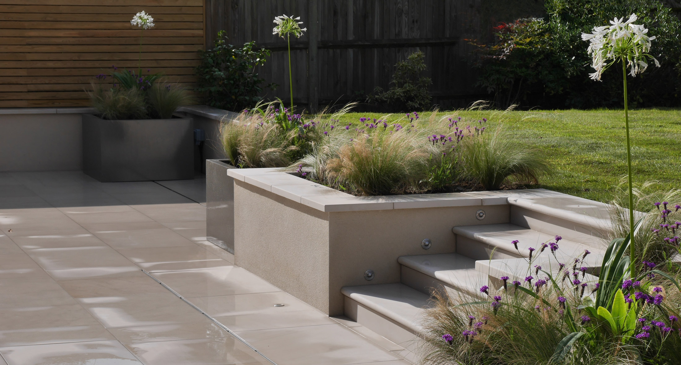a slate grey garden design & landscaping patio showing raised edging and containers